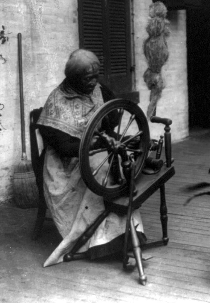 African American woman spinning flax on a spinning wheel.  An unidentified African American woman spinning flax on a spinning wheel.